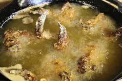 Floured chicken wings go into the hot oil